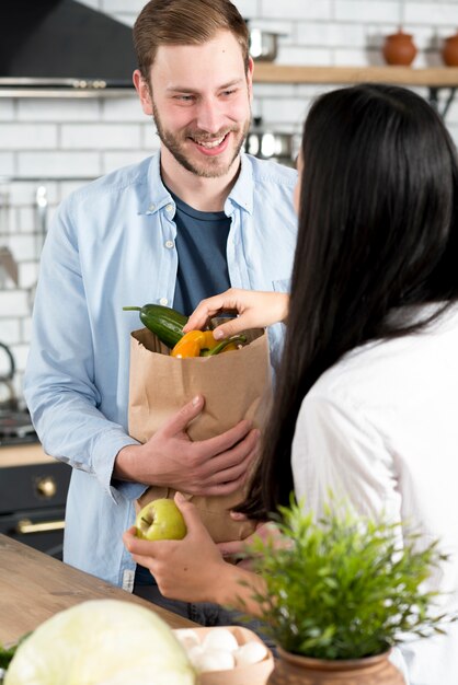 Happy husband standing kitchen holding brown grocery bag