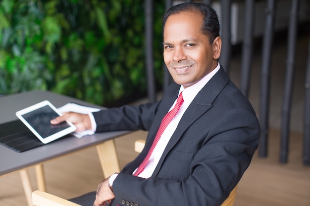 Free photo happy indian business man using tablet in cafe