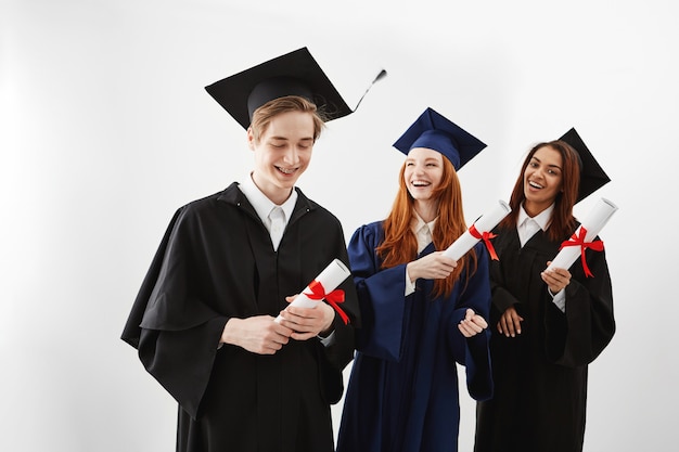 Happy international graduates smiling rejoicing holding diplomas.