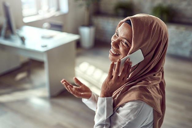 Free photo happy islamic businesswoman making a phone call while working in the office