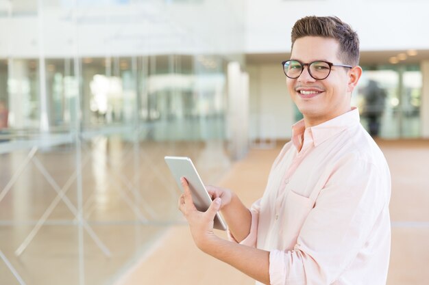 Happy joyful guy in glasses holding tablet