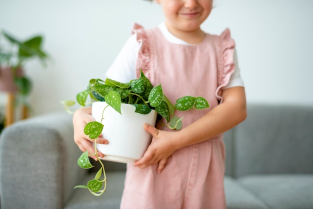 Free photo happy kid holding a small potted plant at home