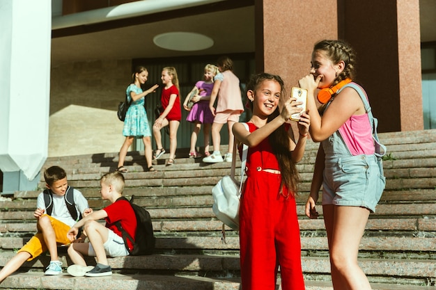 Happy kids playing at city's street in sunny summer's day in front of modern building