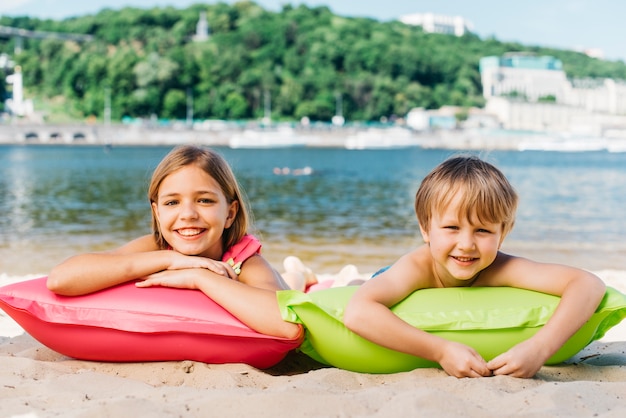 Free photo happy kids relaxing on air mattresses on river coast in summertime