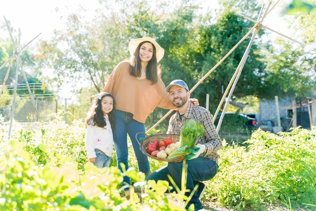 Free photo happy latin family harvesting organic vegetables in garden during sunny day