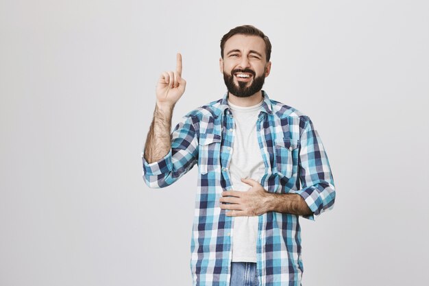 Happy laughing bearded guy pointing finger up