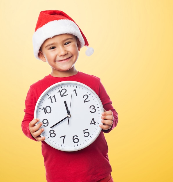 Happy little boy showing a clock