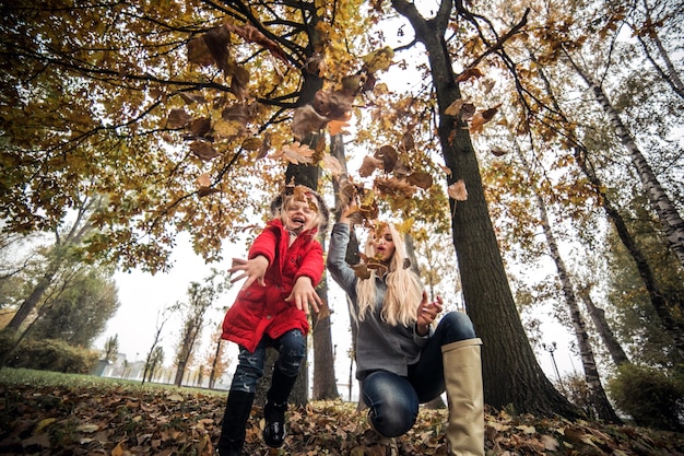 Happy little girl throwing dry leaves