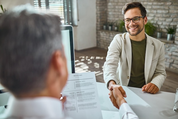 Happy male candidate greeting a member of human resource team on a job interview in the office