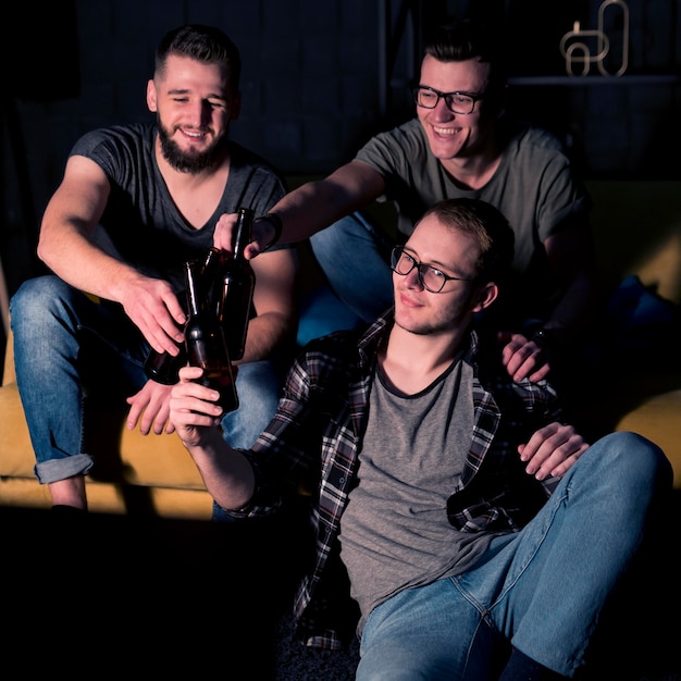 Free photo happy male friends watching sports on tv together while having beer