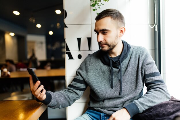 Happy male using smartphone at modern coffee shop