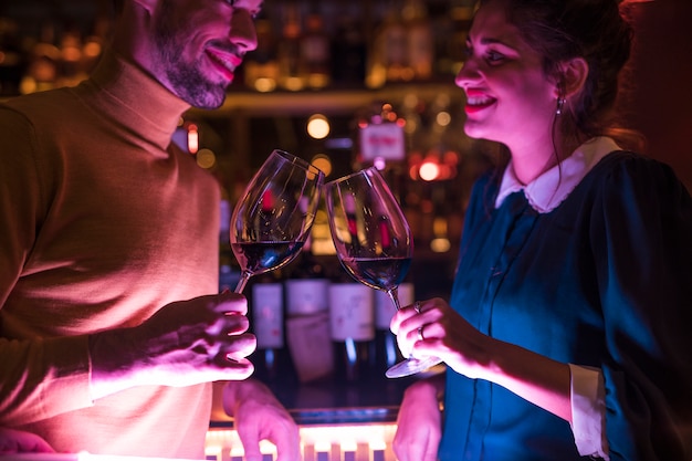 Happy man clanging glasses of wine with cheerful woman