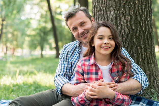 Happy man embracing his daughter while sitting in park