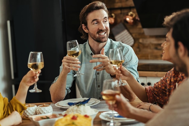 Free photo happy man holding a toast and talking with his friends during a meal at dining table.