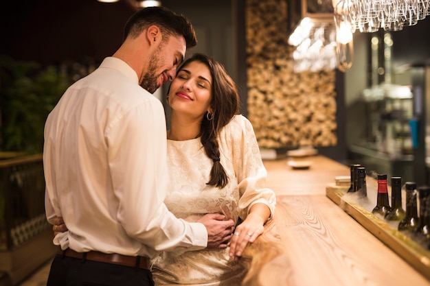 Happy man hugging cheerful woman at bar counter