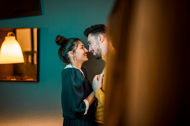 Happy man hugging cheerful woman in room 