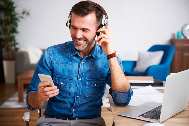 Free Photo happy man listening to music and using mobile phone