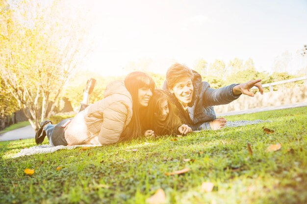 Happy man lying with his family in park pointing at something