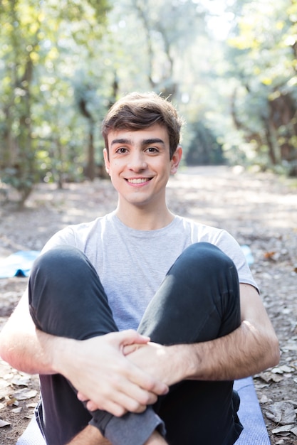 Free photo happy man sitting on the mat outdoors