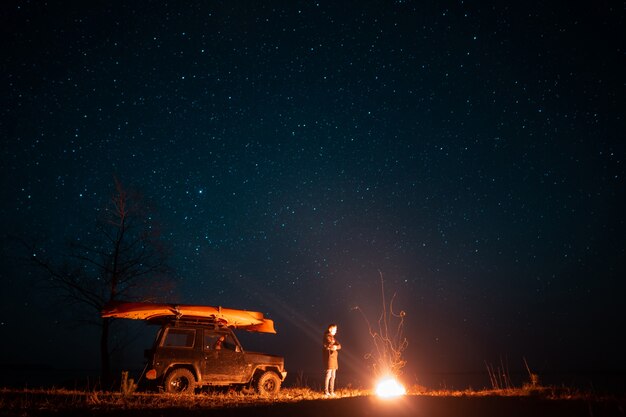 Happy man standing in front burning bonfire