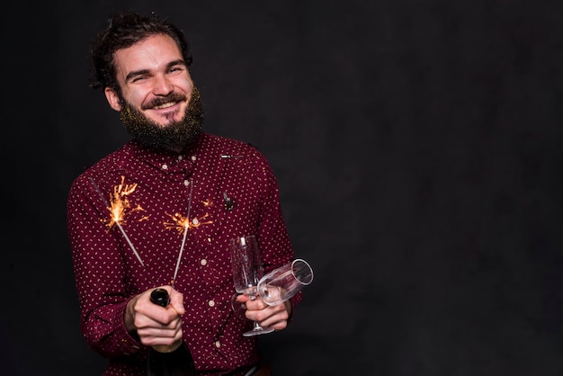 Happy man standing with glasses and sparklers 