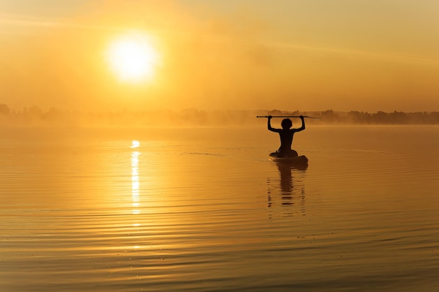 Happy man training on paddle board at morning time