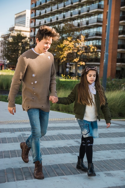 Happy man with his daughter walking together on pavement