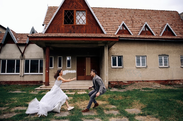 Happy man and woman dressed in official clothing in front of old cozy building running to each other