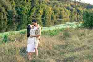 Free photo happy man and woman in nature by the river enjoying each other