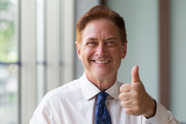 Happy mature businessman showing thumb up