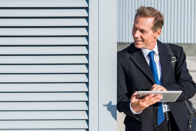 Happy mature businessman using digital tablet at outdoors