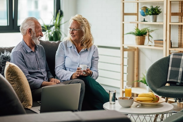 Free photo happy mature couple communicating while enjoying in their coffee time in the living room focus is on man