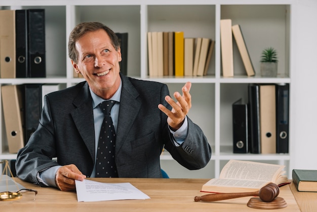 Happy mature lawyer sitting in the court room gesturing