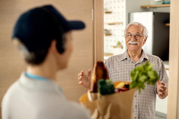 Happy mature man receiving groceries delivery at home