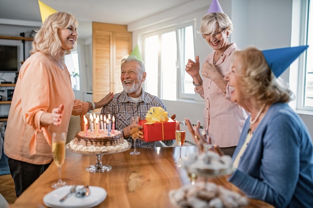 Free photo happy mature people having fun while celebrating birthday at home focus is on man with a birthday present