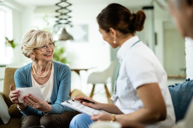 Happy mature woman communicating with female doctor at home