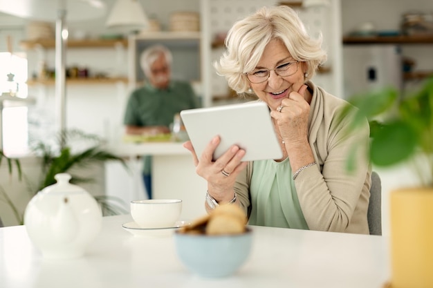 Free photo happy mature woman using digital tablet at home