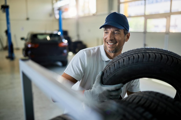 Free photo happy mechanic working with tires at car service workshop