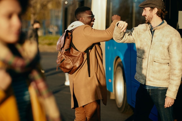 Happy men elbow bumping while greeting at bus station