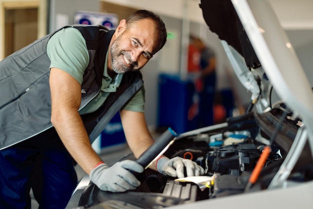 Free Photo happy mid adult mechanic working in auto repair shop and looking at camera