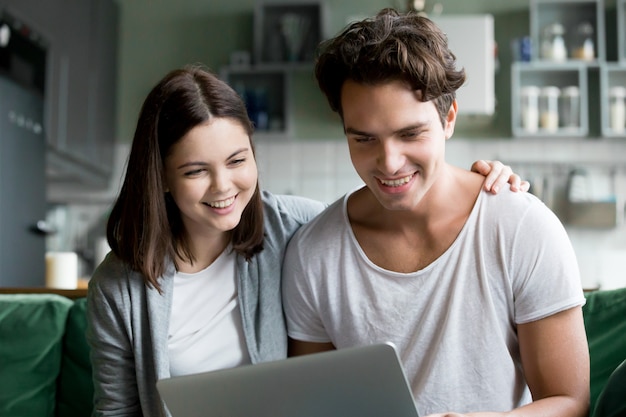 Happy millennial couple smiling looking at laptop screen making videocall