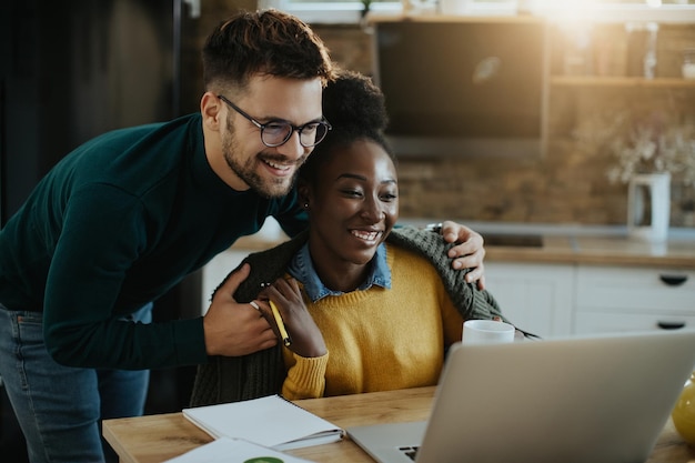 Happy mixedrace couple reading an email on laptop at home