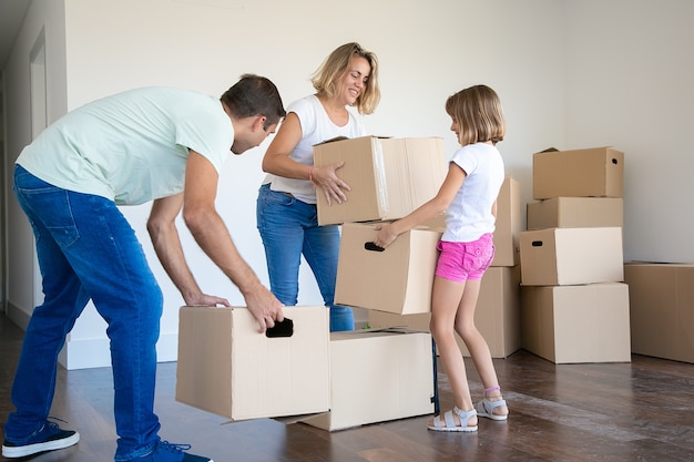 Happy mom, dad and kid holding cardboard boxes and moving to new house or apartment