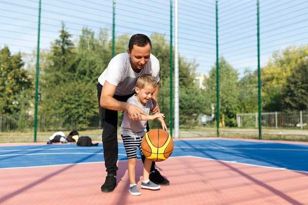 Happy monoparental family learning how to play basketball