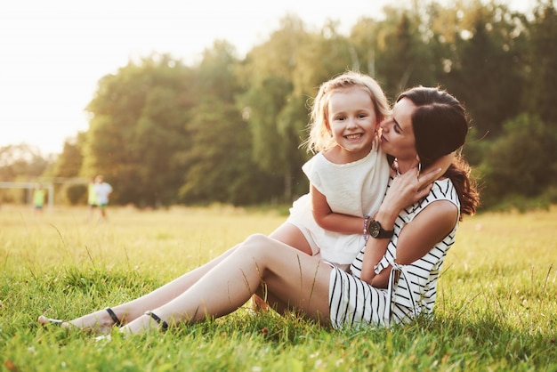 Happy mother and daughter hugging in a park in the sun on a bright summer of herbs.