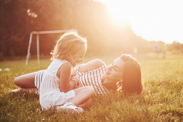 Happy mother and daughter hugging in a park in the sun on a bright summer of herbs.