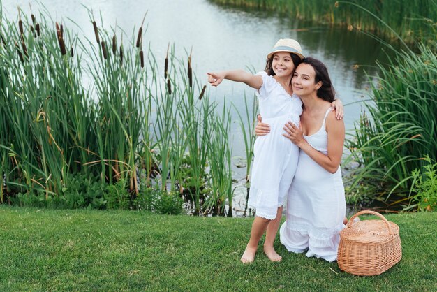 Happy mother and daughter posing by the lake