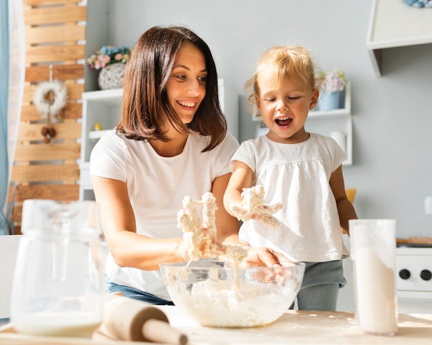 Happy mother and daughter preparing dough