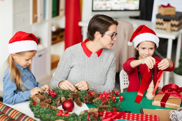 Happy mother and daughters decorating the christmas wreath