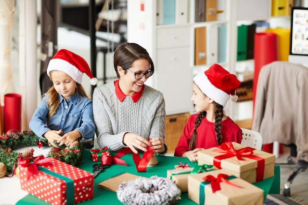 Happy mother and daughters wrapping Christmas presents